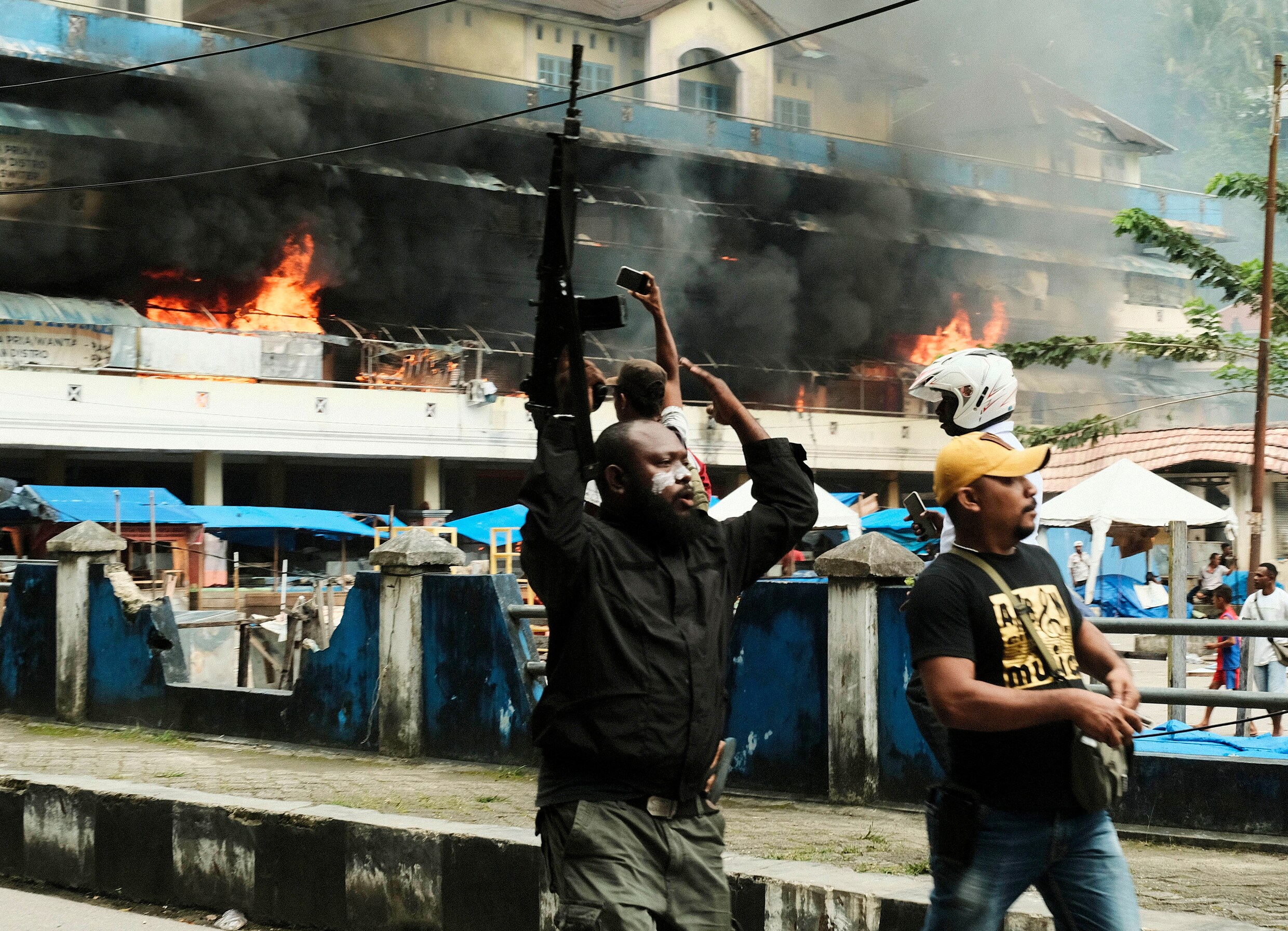 Foto van vorige week: een Indonesische politieagent met geweer patrouilleert bij de markt van Fakfak in West-Papua, waar brand uitbrak na gewelddadige protesten.