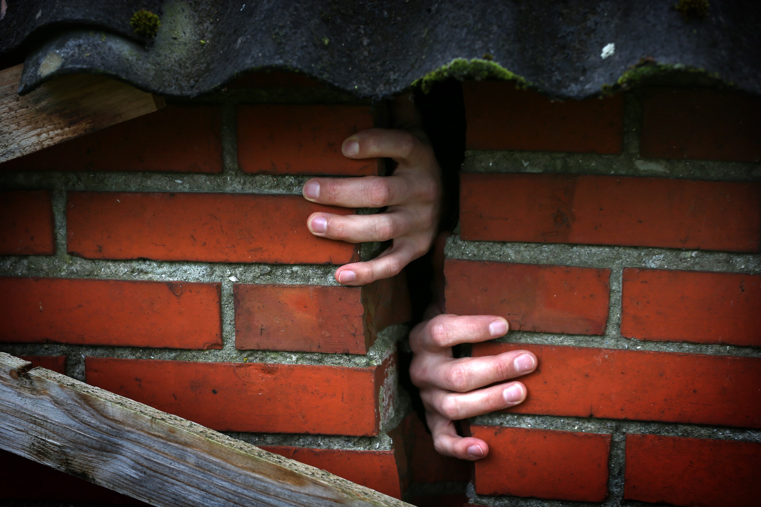 Een bewoner steekt zijn handen door een scheur in de muur van een woning in Bedum.