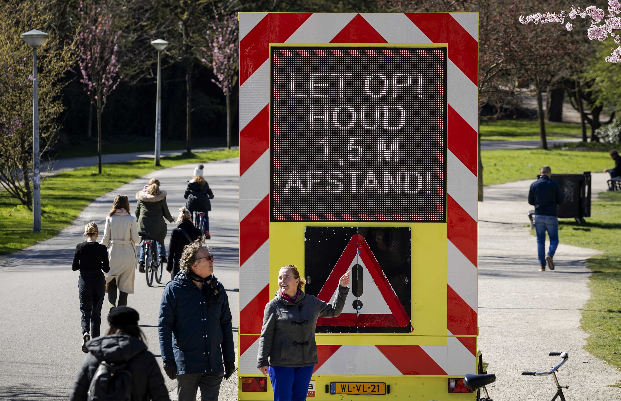 In het Vondelpark in Amsterdam staat een bord met de waarschuwing om anderhalve meter afstand te houden van elkaar te houden vanwege het coronavirus.