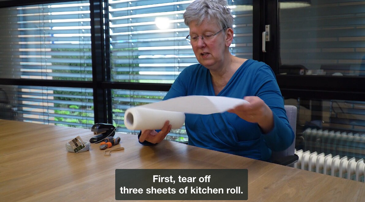Zelf een mondkapje maken met keukenpapier. Beeld uit een instructievideo van Buurtzorg Nederland.