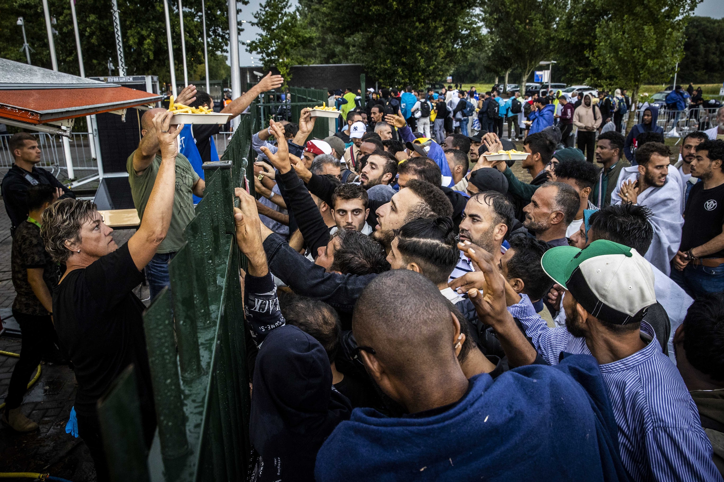 asielzoekers-krijgen-eten-uitgereikt-over-het-hek-bij-het-terrein