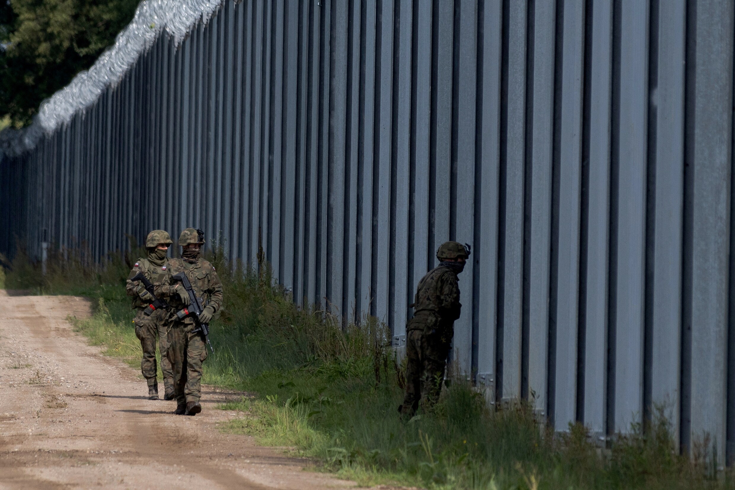poolse-militairen-patrouilleren-langs-een-hek-die-migranten-moet
