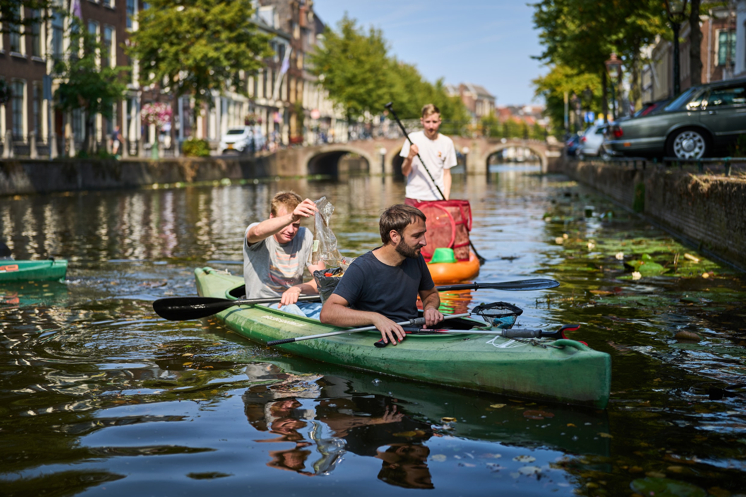 Deelnemers van De Grachtwacht vissen zwerfafval uit de Leidse grachten.