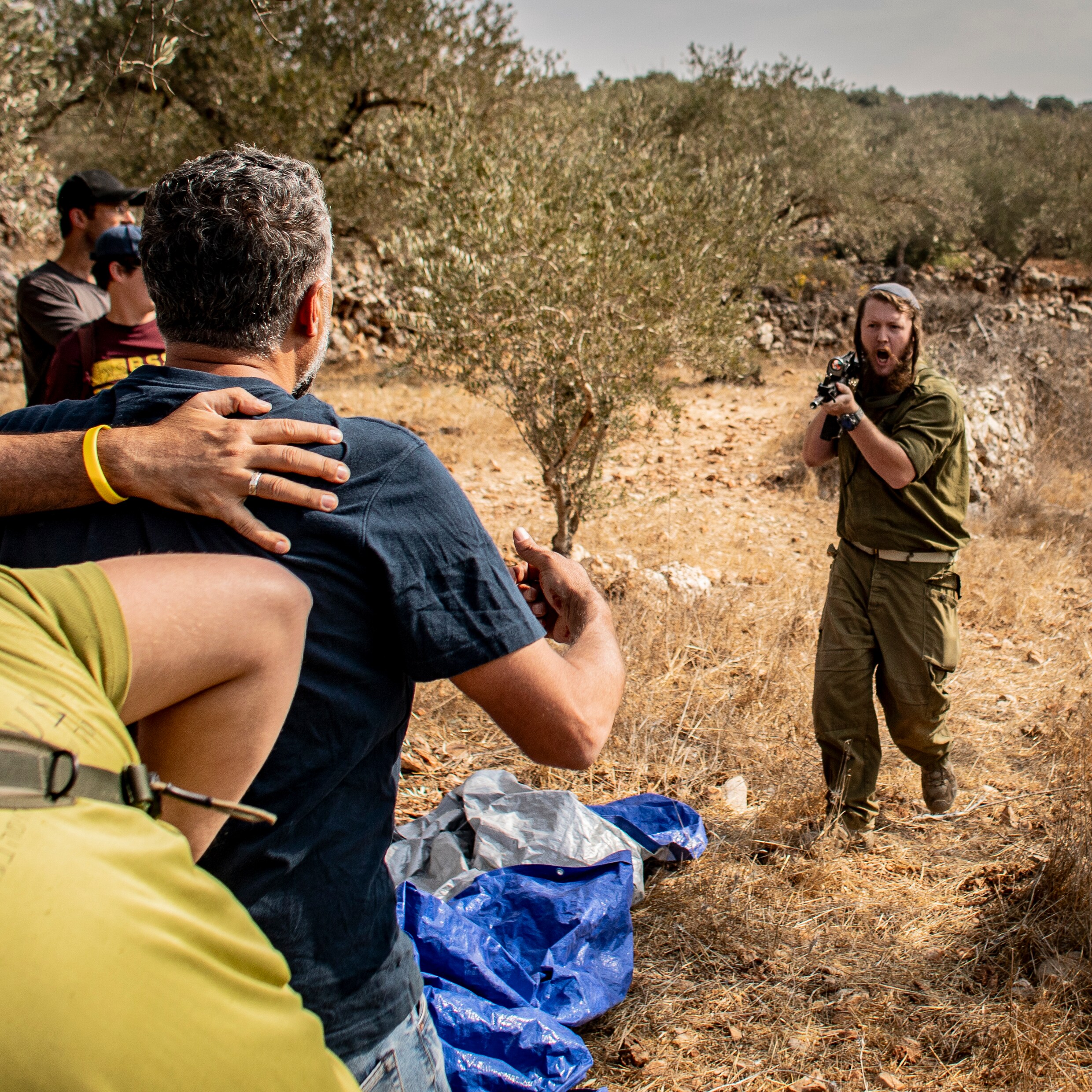 Een Israëlische kolonist richt zijn wapen op een groep Palestijnse boeren en vredesactivisten die samen olijven oogsten in het Palestijnse Deir Istiya op de Westelijke Jordaanoever, vlak bij de illegale nederzetting Revava.