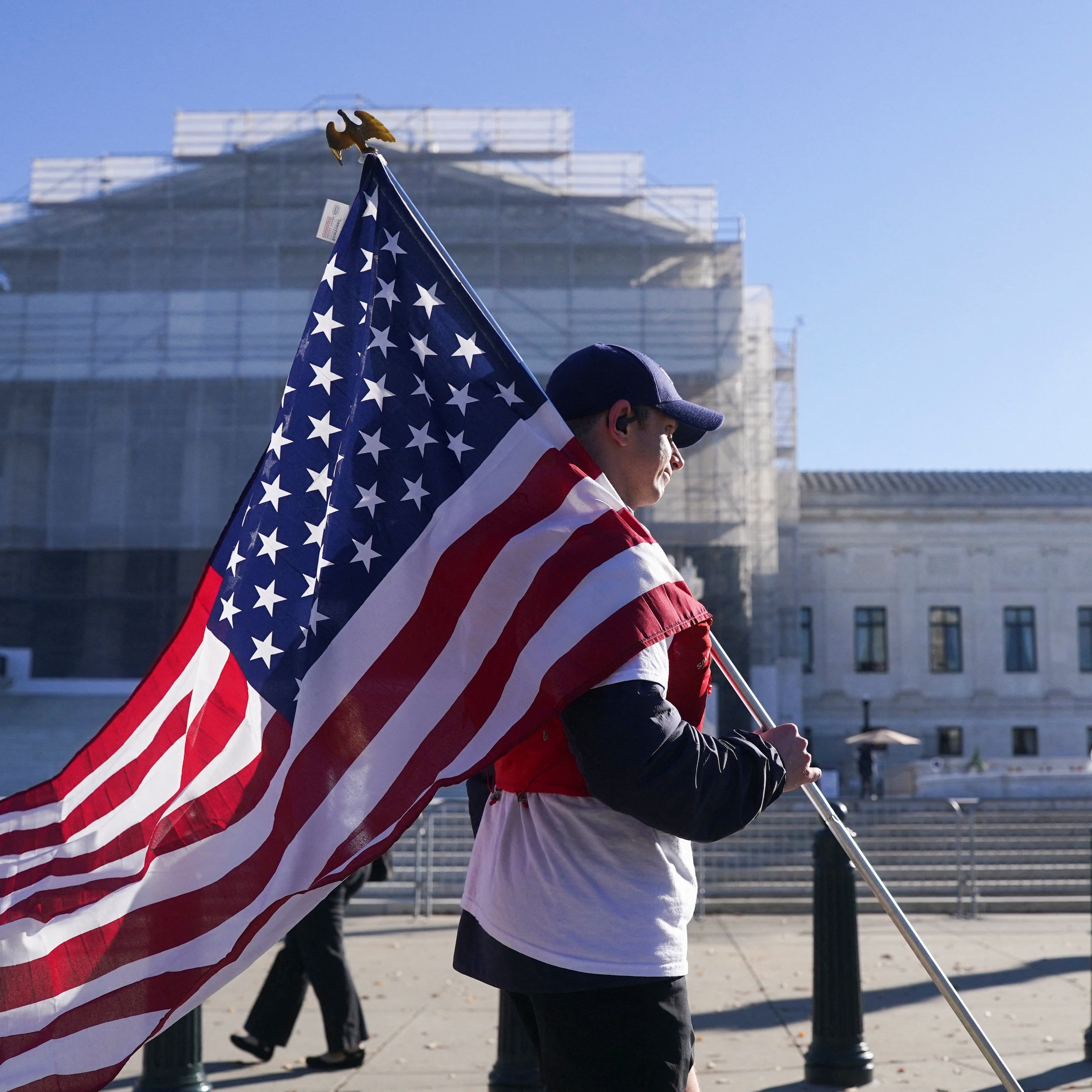Een Amerikaan loopt voor het hooggerechtshof in Washington waar de rechters zich buigen over de wettigheid van Donald Trumps handelstarieven.